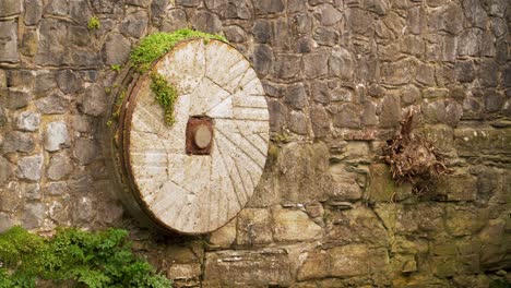 4k old mill stone decorating a wall in one of the affluents of the river tone in taunton somerset