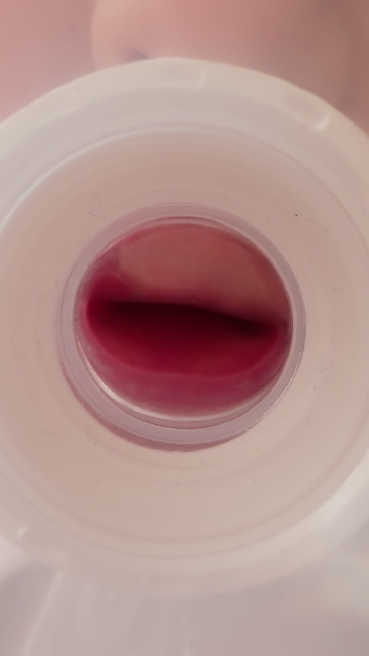 Child takes transparent plastic bottle with nipple standing in kitchen. Hungry little boy sucks nipple and puts bottle on table macro low angle shot