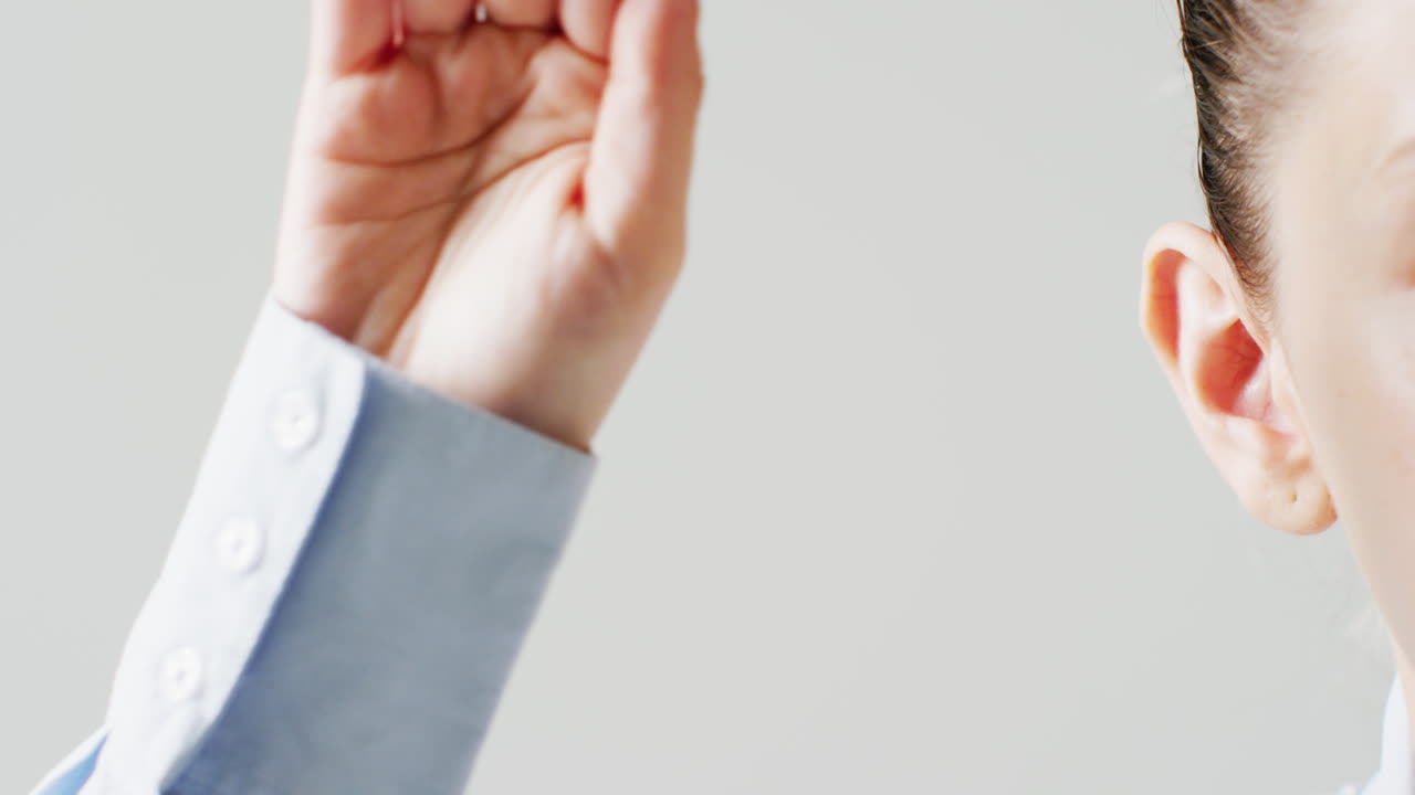 회색 복사 공간과 함께 더 명확하게 듣기 위해 귀 뒤에 손을  ⁇ 는 백인 여성의 비디오 세부 사항