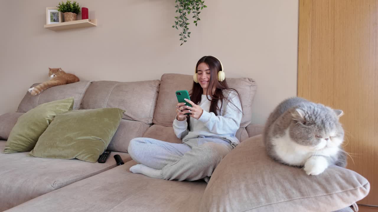 Woman relaxing at home with cats and listening to music