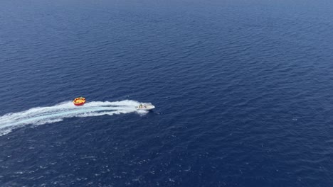 Tourists-On-Twister-Ride,-An-Inflatable-Pulled-By-A-Speedboat-Bouncing-And-Twisting-In-The-Ocean