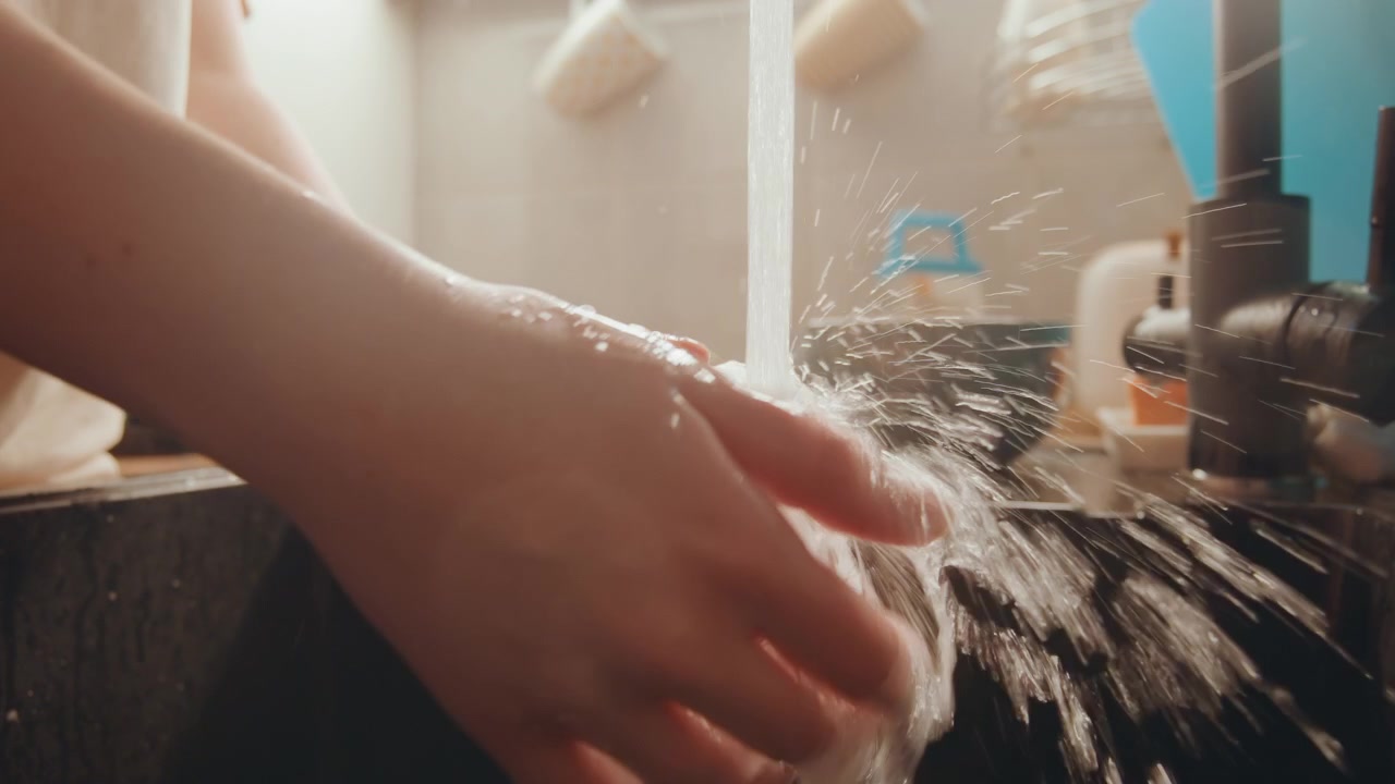 Des mains créent de la mousse sur une surface en verre. Gros plan sur des mains appliquant du savon, créant de la mousse sur du verre dans l'eau. Vue détaillée de mains créant des bulles de savon sur du verre pendant le nettoyage sous l'eau courante.