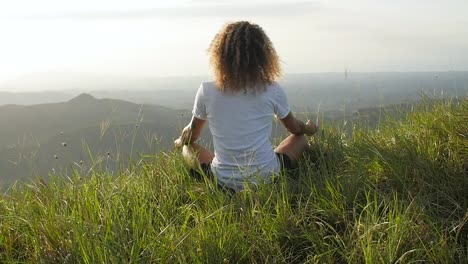 Latin-American-man-meditating-in-lotus-position-at-a-hill-in-Valle-de-Anton-Panama,-Pedestal-rising-slow-motion-shot