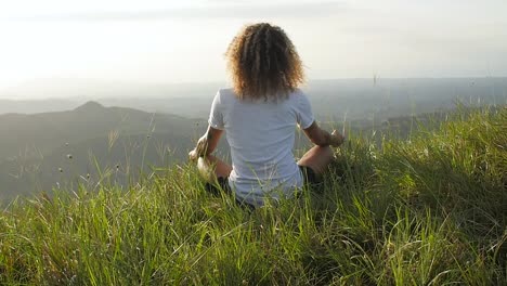 Latin American man meditating in lotus position at a hill in Valle de Anton Panama, Pedestal rising slow motion shot