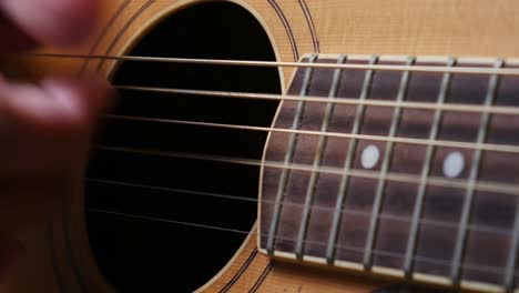 close up shot of man's hand playing guitar with picking technic