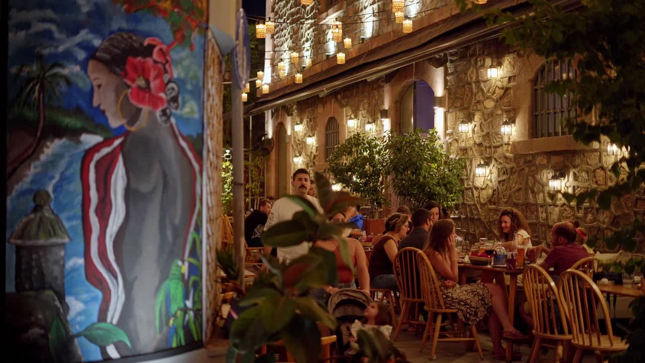 Traditional Greek taverna vibrant atmosphere at night, Outdoor Cafe colorful wall art, Handheld shot