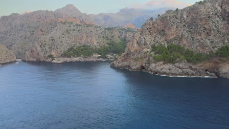 Rotating-drone-shot-of-Sa-Calobra-and-Torrent-de-Pareis-from-afar-above-the-Mediterranean-sea-in-Mallorca,-Spain