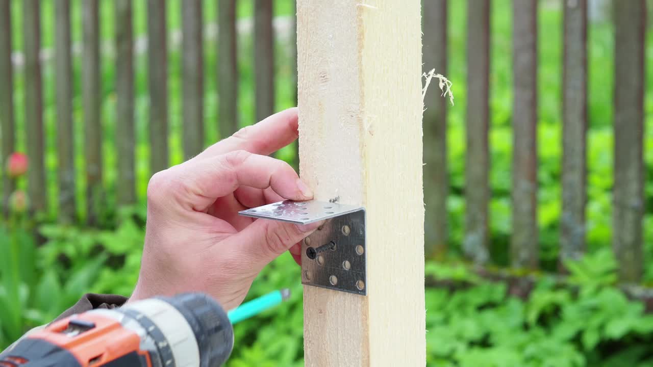 The worker screws the metal corner to the board with a screwdriver. Construction. close-up.