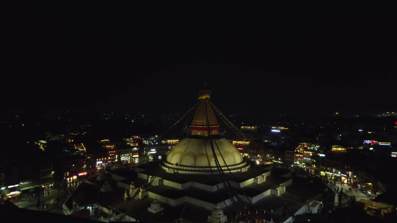 A serene night drone view of Boudhanath Stupa, a UNESCO world heritage site. The sacred Buddhist landmark glows beautifully above Kathmandu’s peaceful evening skyline