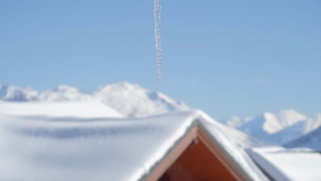 Einzelner-Schmelzender-Eiszapfen-Mit-Klarem-Blauen-Himmel-Und-Berg-Im-Hintergrund