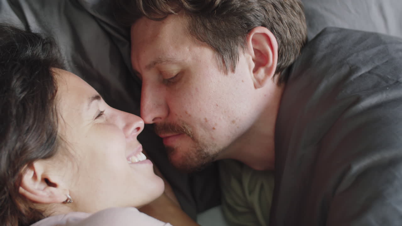 una pareja besándose en la cama.