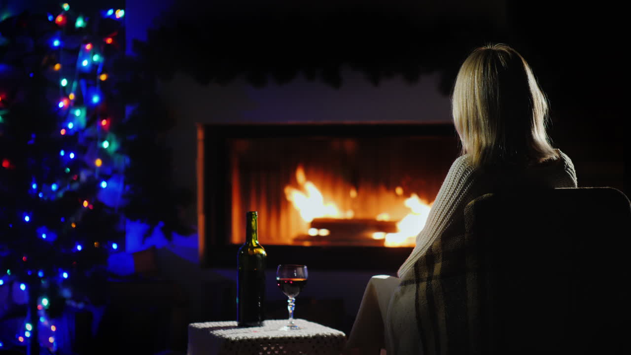 mujer solitaria se encuentra con la navidad sola junto a la chimenea con una copa de vino