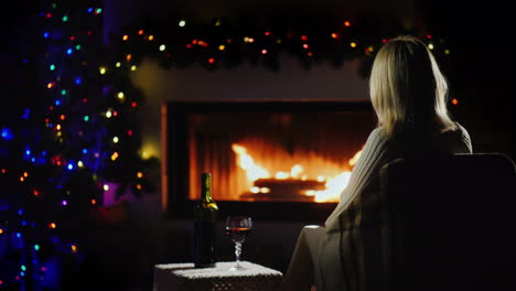 lonely woman meets christmas alone by the fireplace with a glass of wine