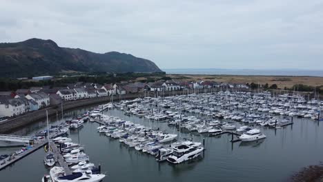 Aerial-view-Wealthy-luxury-yachts-and-sailboats-moored-in-quaint-Conwy-town-harbour