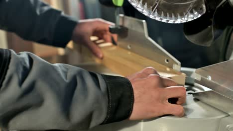 a young carpenter installs a wooden work piece in a circular sawing machine