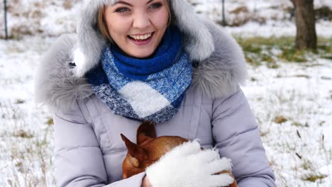 mujer jugando con su pequeño perro fuera del invierno