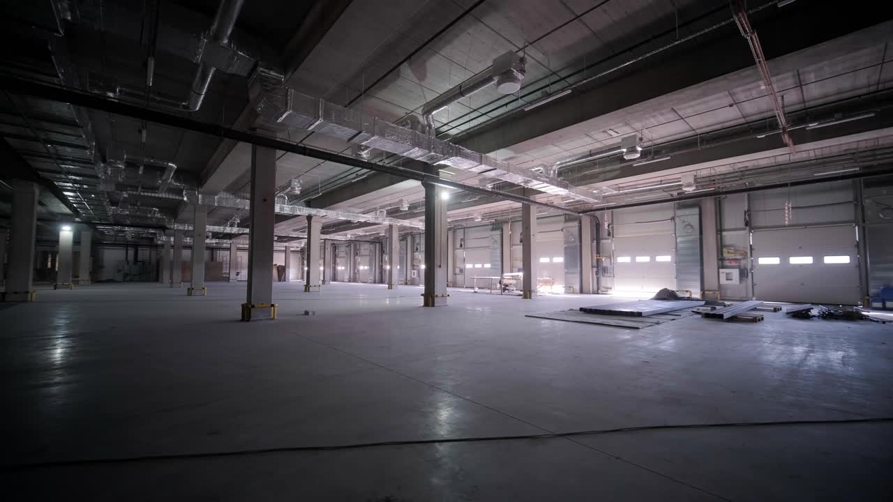 Stort og moderne lager under opførelse, med metalreoler og andet industrielt udstyr.