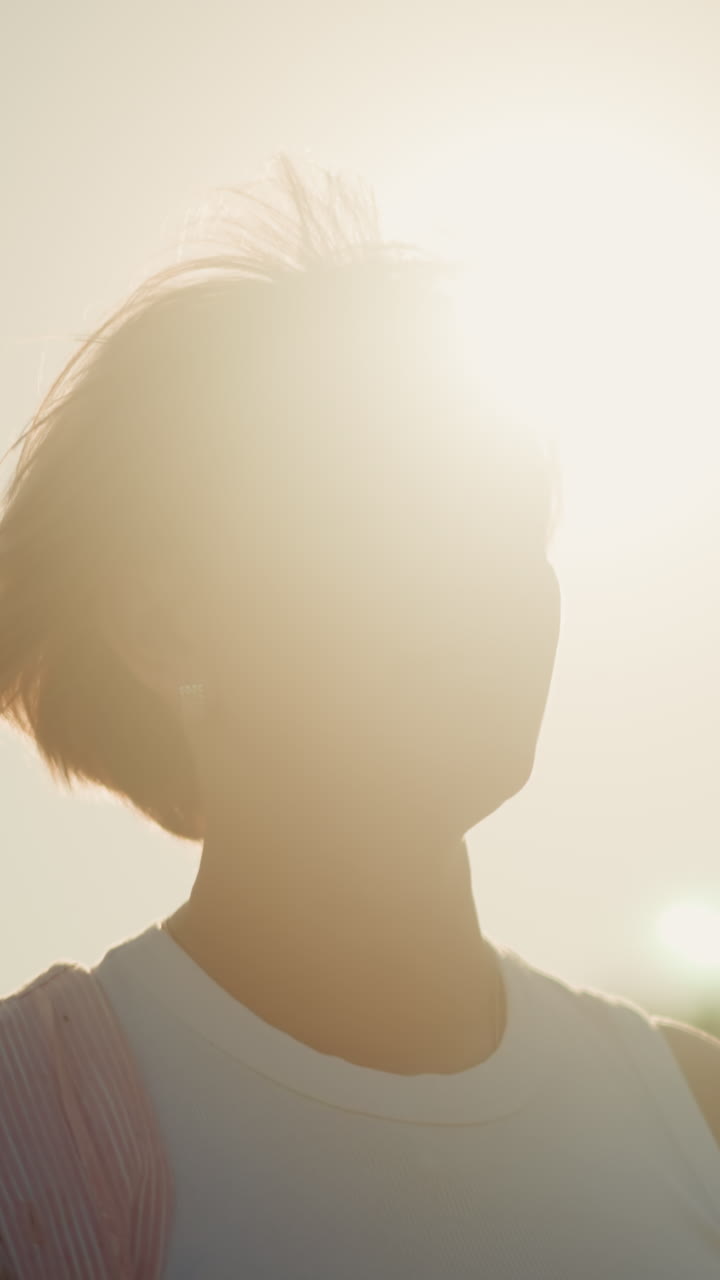 바에 서있는 여성, 밝은 빛이 그녀의 뒤에 빛나고, 멀리서 무언가를 바라보면서 따뜻하게 미소 짓고, 빛은 그녀의 머리를 둘러싼 홀로 효과를 만니다.