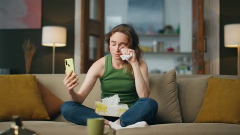 mujer deprimida llamando por teléfono al sofá interior. niña triste sosteniendo servilleta sufriendo