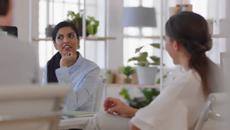business women brainstorming discussing strategy having conversation in relaxed office workspace