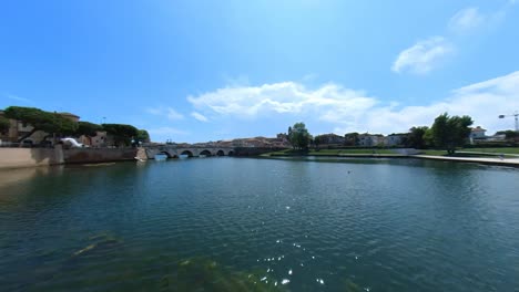 birds flying towards the roman tiberius bridge in rimini, italy