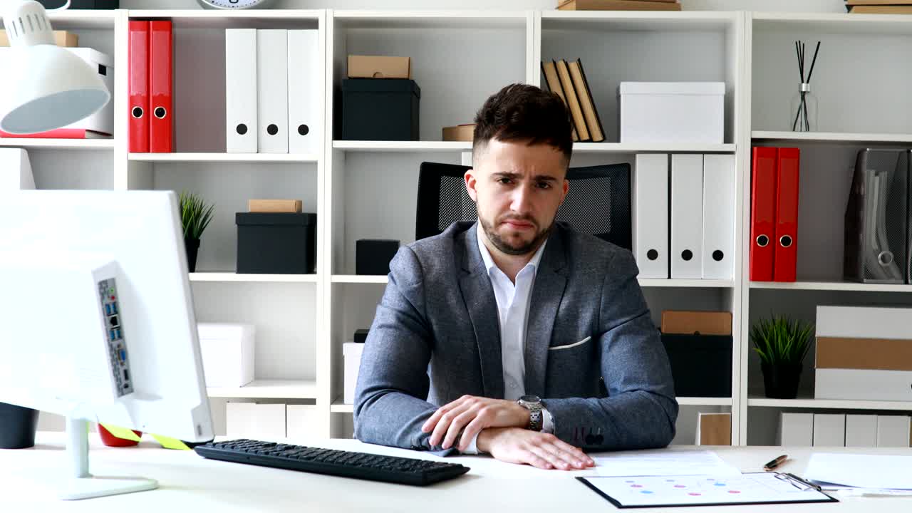 direttore in giacca grigia seduto a tavolo in ufficio bianco e scuotendo la testa negativamente
