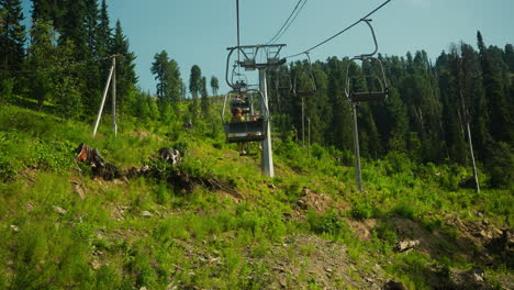 tourists lift to top of mountain on cable car in summer. enjoying leisure time together on holiday. hotel area surrounded by hills and forest slow motion