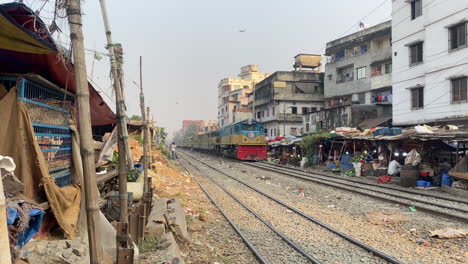 local passenger train passing through city market in dhaka, bangladesh - handheld shot