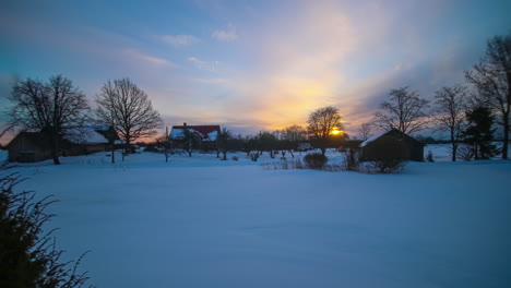 Amanecer-Sobre-Paisaje-Nevado-Con-Cabañas-En-El-Campo-Letonia,-Timelapse