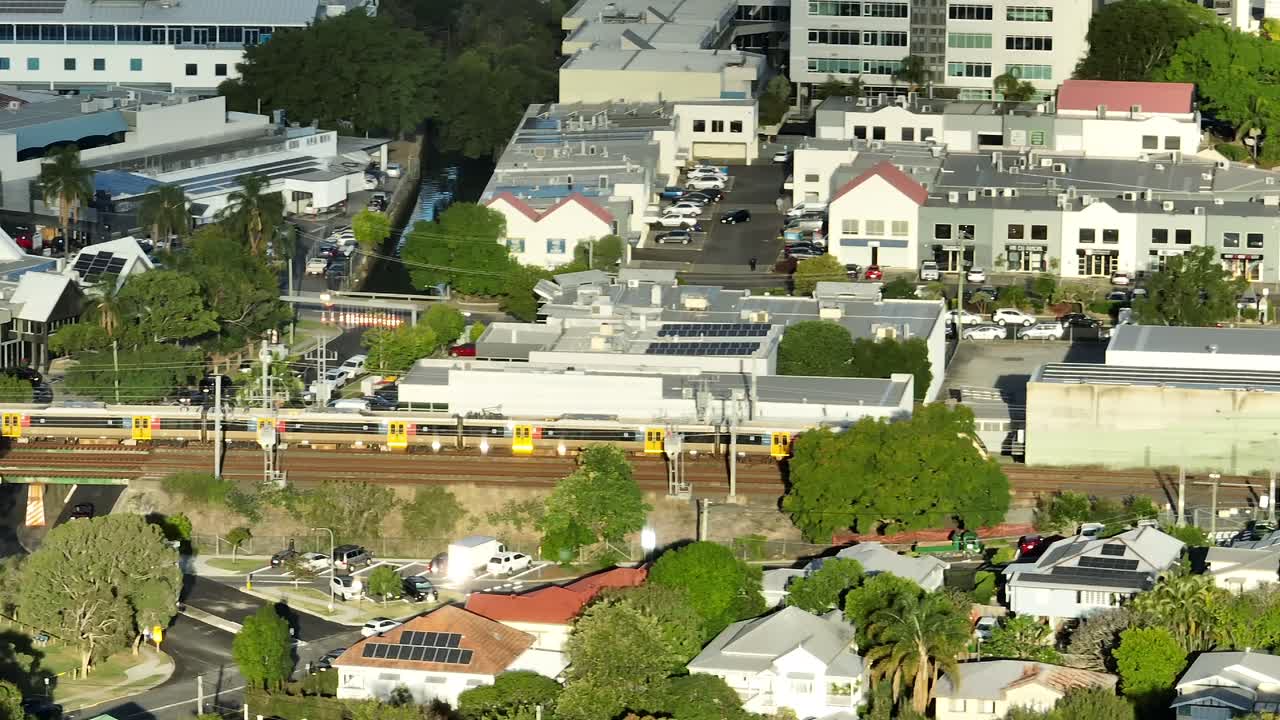 Aerial panning shot tracking a Brisbane Train as it drives through Brisbane's inner suburbs