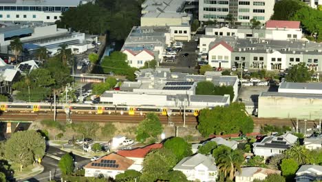 Aerial panning shot tracking a Brisbane Train as it drives through Brisbane&#039;s inner suburbs