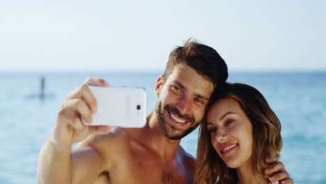una pareja tomando una selfie con su teléfono móvil en la playa 4k