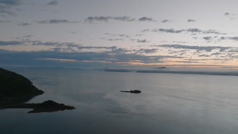 aerial: drone shot slowly panning across the ocean showcasing the whitsunday islands on the horizon during sunrise, qld, australia
