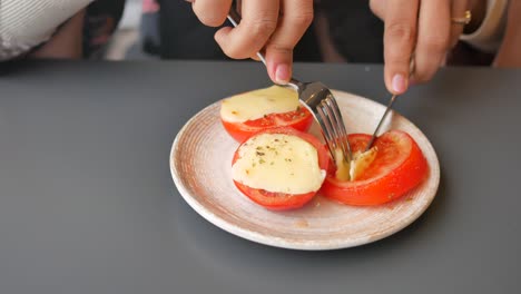 persona comiendo tomates horneados con queso
