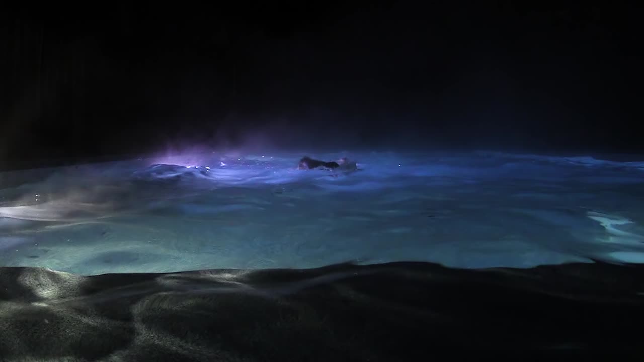 Person swimming in a hot tub at night