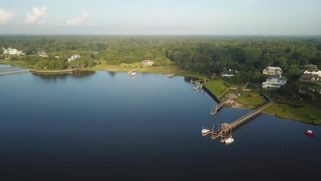 Peaceful-sunrise-drone-right-pan-of-shore-land,-piers,-waterway,-houses,-and-marsh-at-Trails-End-Park-in-Wilmington-North-Carolina