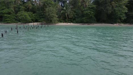 Antena---Flotando-Sobre-El-Agua-Azul-Profundo-Mirando-Hacia-La-Isla-Boscosa