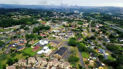 aerial footage of a drone flying over residential houses overlooking a busy highway with moving traffic in a suburb of yellow wood park durban