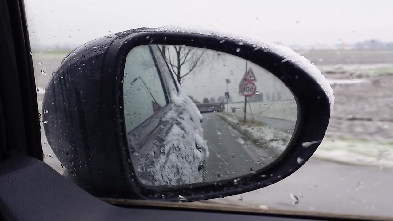 Udsigt fra et sidespejl med sne. Denne optagelse er bedst til vinter, kolde årstider, rejser om vinteren, bilture og kommercielle temaer.