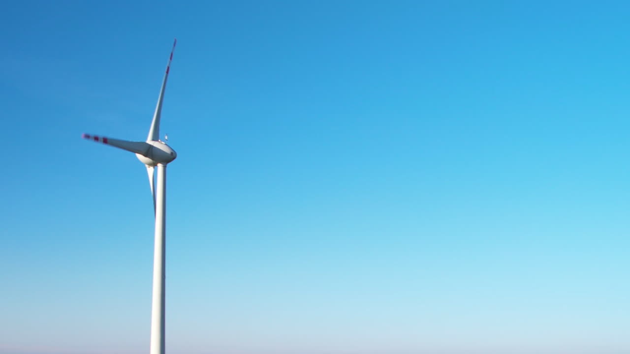 한  ⁇ 색과 빨간색의 풍력 터빈이 파란 하늘을 배경으로 복사 공간을 가지고 있습니다.