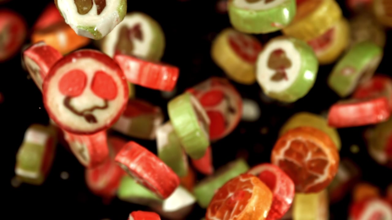 Caramelos de frutas de colores cayendo a cámara lenta sobre fondo negro