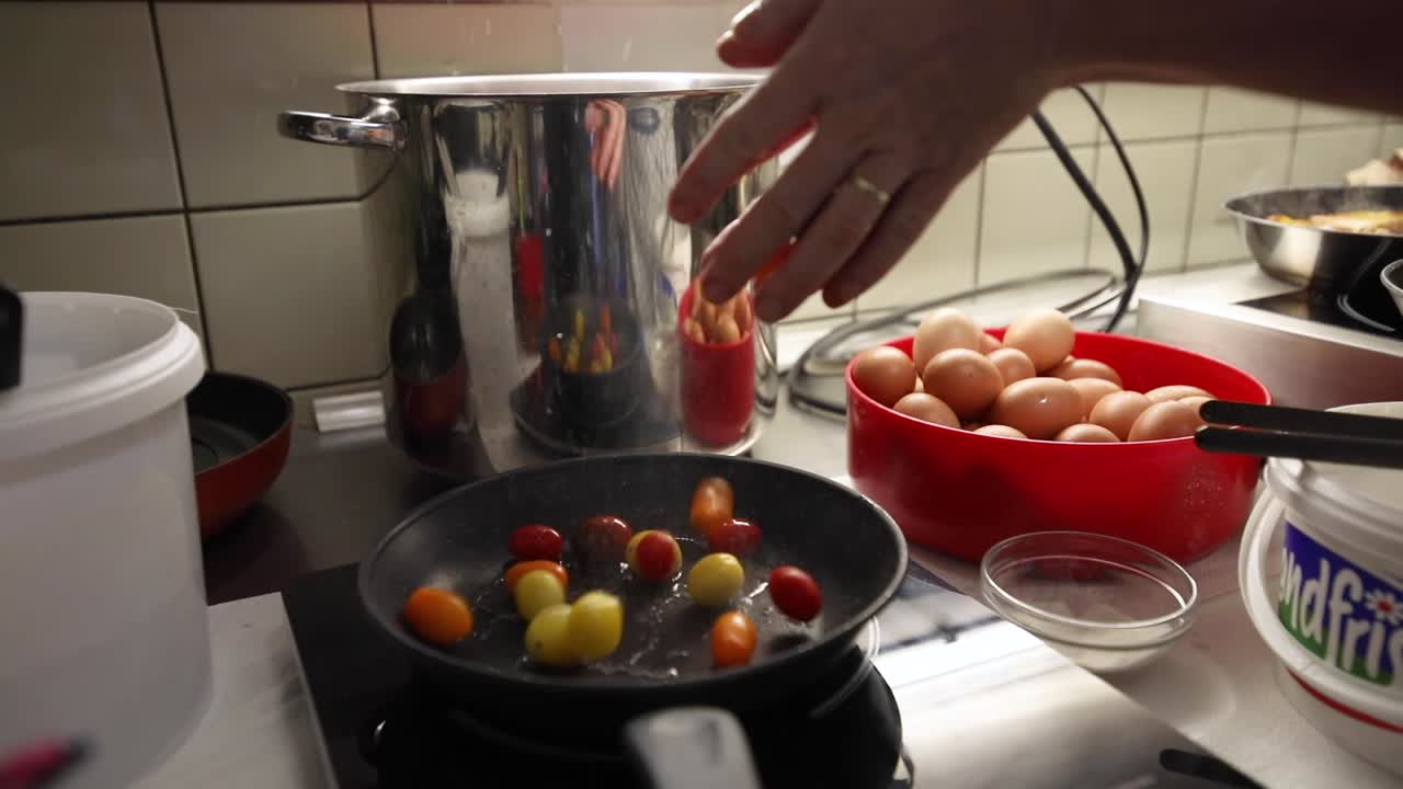 mano de mujer poniendo tomates en la sartén - freír tomates frescos