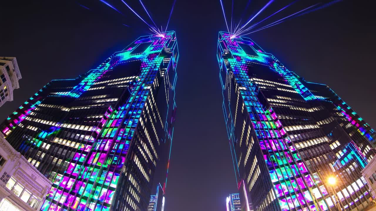 Twin skyscrapers illuminated with vibrant laser lights at night, showcasing a dynamic light display that captivates the urban skyline and enhances the atmosphere