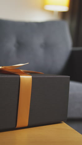 vertical video of present in gift wrapped box decorated with ribbon on table in lounge 2