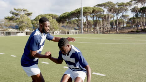 helping teammate stand, rugby african american male players training on field, sports, copy space