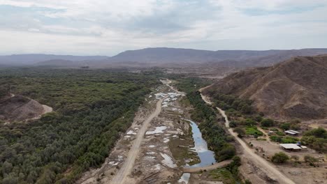 la orilla secada del río transformada en una carretera y los camiones que conducen en ella entregando materiales de construcción como la arena en el norte de perú.