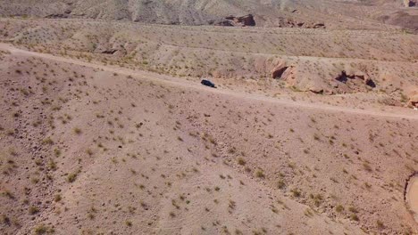 Vista-Aérea-Lejos-De-Un-Automóvil-Estacionado-En-Un-Camino-De-Tierra-Del-Desierto,-En-El-Soleado-Lavado-De-Kingman,-EE.UU.---Tire-Hacia-Atrás,-Tiro-De-Drones