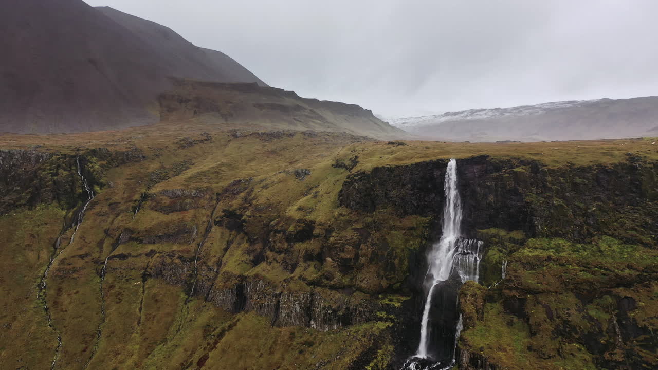 vuelo de drones hacia una cascada arrastrada por el viento en islandia
