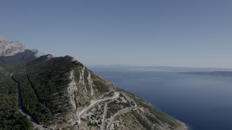 Video-De-Drones-Sobre-El-Paso-De-Montaña-De-La-Guerra-De-La-Patria-En-La-Orilla-Del-Río-Makarska,-Toma-Frontal-Avanzando-Dejando-Atrás-El-Camino-Y-Terminando-En-La-Cima-De-La-Montaña