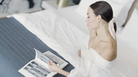 woman reading fashion magazine in bed